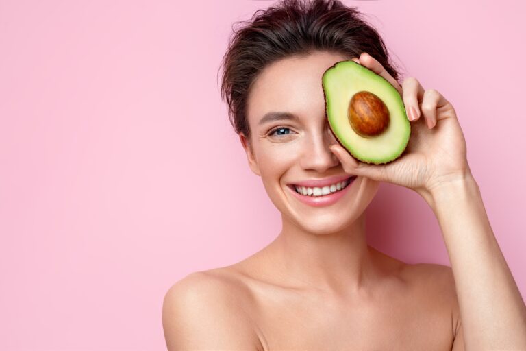 woman holding avocado to eye