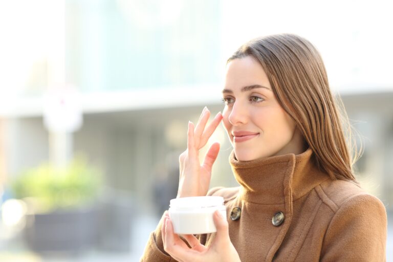 woman in coat applying eye cream