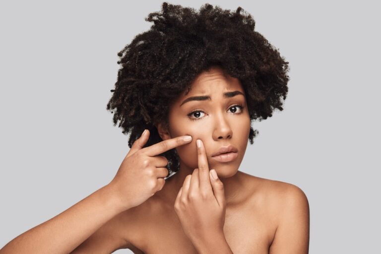 concerned black women attempting to pop pimple on her otherwise clear skin